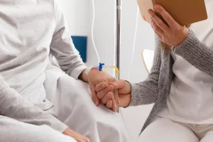 Idosa usa um extensor para infusão enquanto recebe medicamentos na veia e uma enfermeira segura sua mão