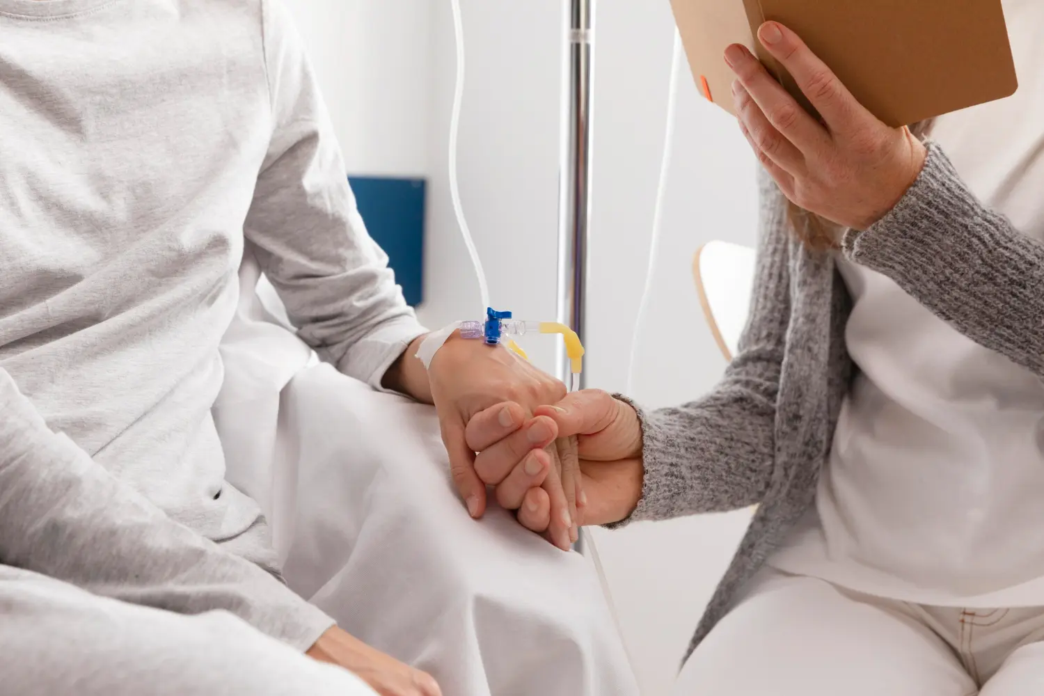 Idosa usa um extensor para infusão enquanto recebe medicamentos na veia e uma enfermeira segura sua mão